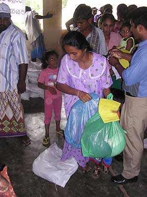 A woman picks up a bag of supplies after a tsunami hits Sri Lanka in 2004.