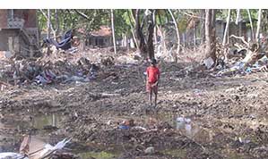 Boy standing the the middle of what was his village in Sri Lanka after a tsunami hit in 2004